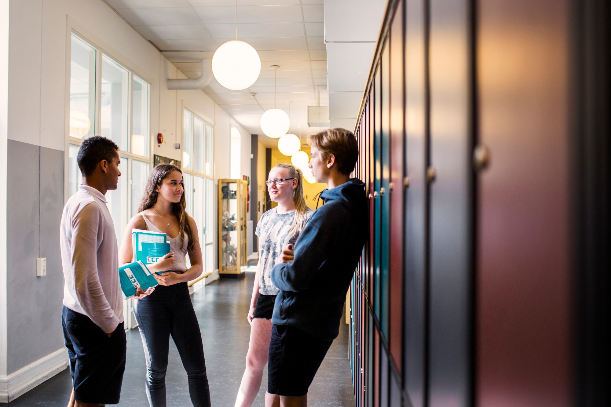 Four pupils talking in a school corridor lined with lockers
